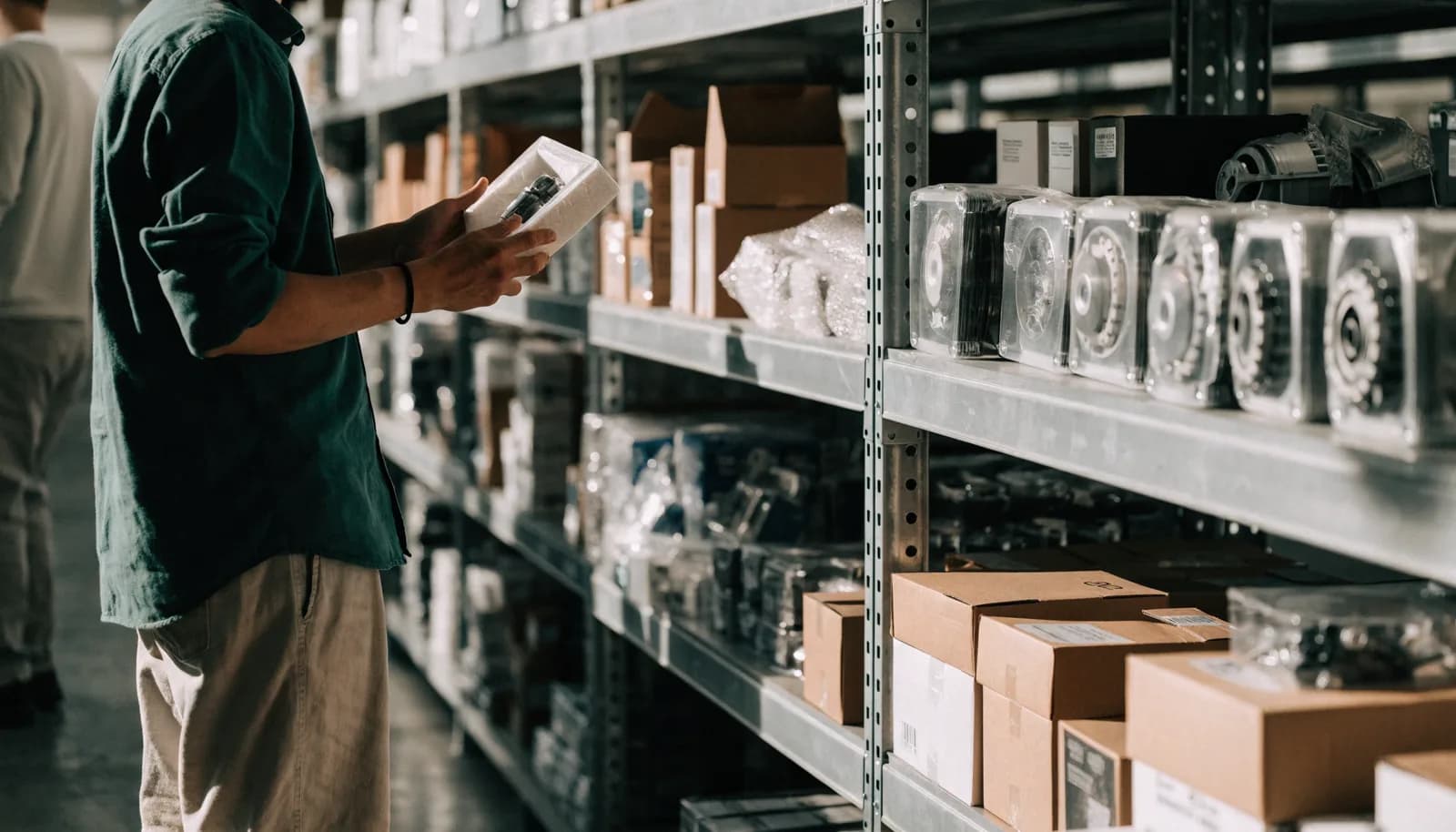 Shopper inspecting a boxed automotive part in a bright liquidation warehouse aisle