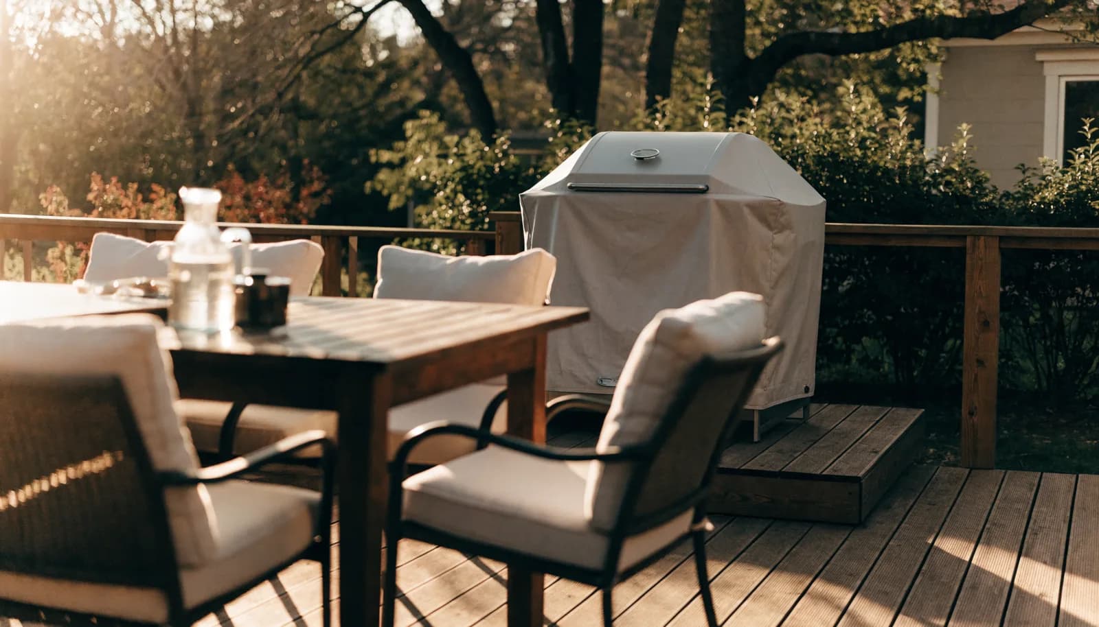 Sunlit backyard patio furniture set and grill on a wooden deck at golden hour