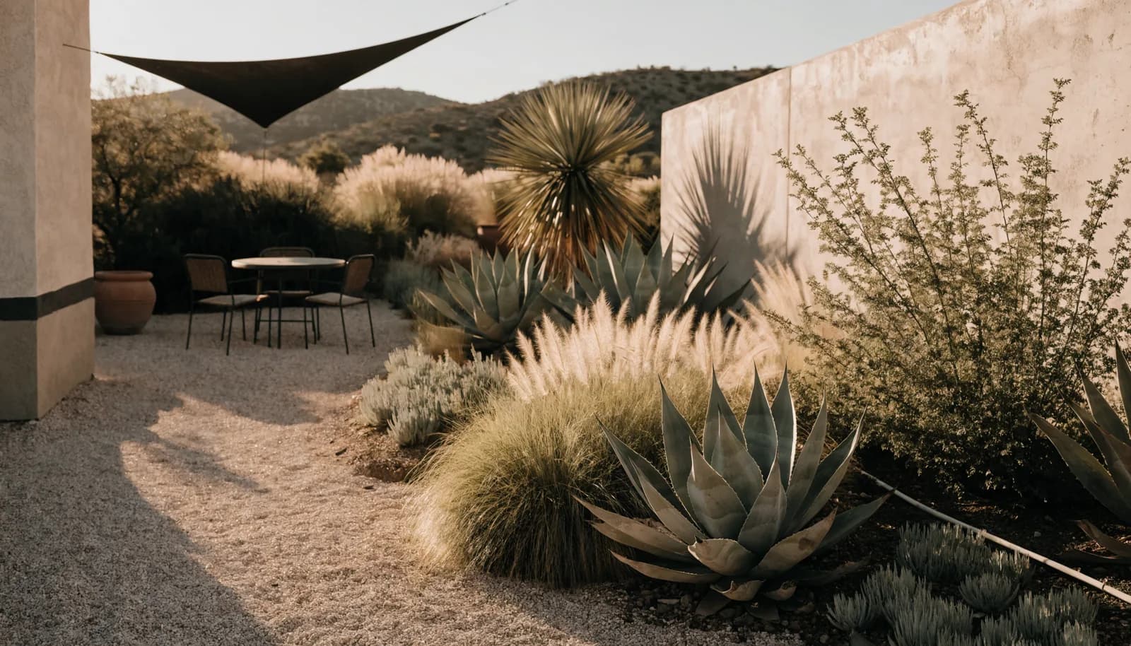 Shaded desert backyard patio at golden hour with gravel landscaping, agave, and a small outdoor dining set
